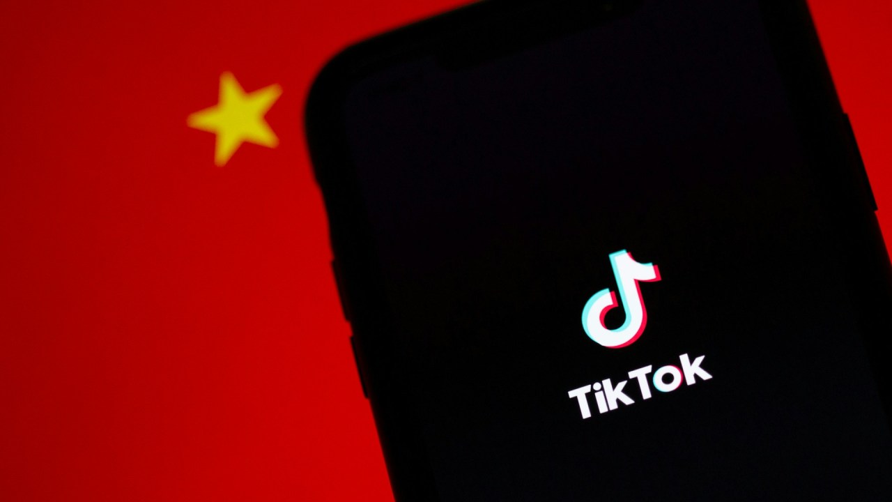 Celular com aplicativo do TikTok aberto, com a bandeira da China ao fundo.