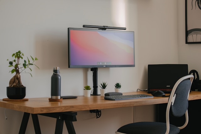 mesa de estudos, com monitor e garrafa de água.