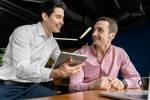 Dois homens conversando em mesa de ambiente corporativo