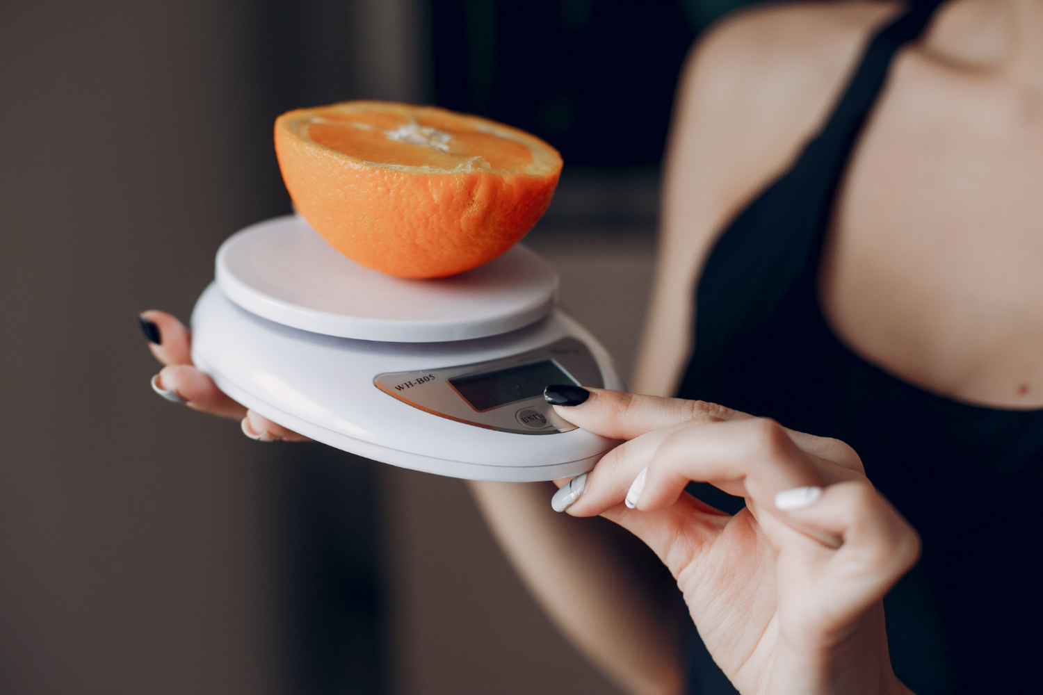 Mulher pesando metade de laranja em balan&ccedil;a