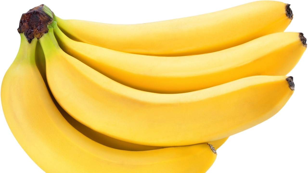 Um cacho de bananas maduras, com casca amarela vibrante e hastes esverdeadas, sobre fundo branco
